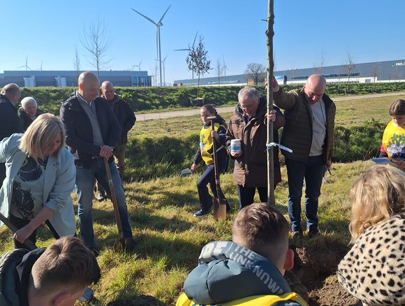 Kinderen zijn druk met het planten van een boom, links wethouder Kools.